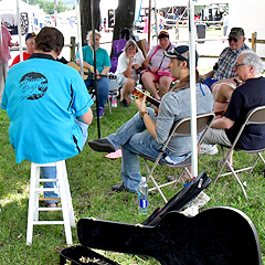 A group of people sit in a circle playing instruments