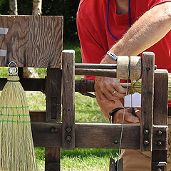 A man uses a traditional machine to make a broom