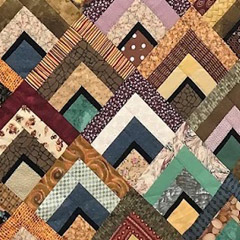 Close-up of a quilt by Narda LeCadre, done in earth tones with overlapping angles that suggest mountains