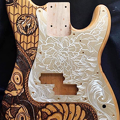 An electric guitar body decorated by Aron Rook, with etched peony flowers on the pick-guard and Asian-inspired fish on the wood