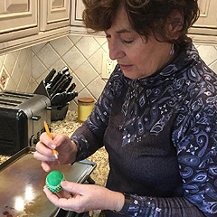 A woman makes a traditional Polish Easter egg, drawing a pattern on a dyed egg with melted wax