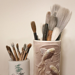Diana Meng’s paintbrushes in two jars, the smaller painted with bamboo, the larger decorated with goldfish
