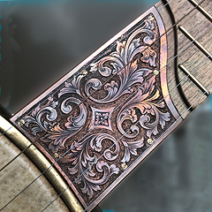 A copper scoop plate with iridescent engravings, set into the end of a fretboard where it meets the round part.