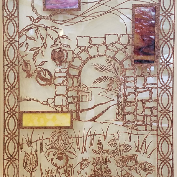 A traditional paper-cut creation, executed in brownish marbled film, sandwiched in thick acrylic and suspended in front of a lighter colored wall. The design shows a stone archway, with various flowers in the foreground, and an abstract border on the left and right edges. Looking through the archway, one sees a date palm, a roadway, and a building suggestive of Israel. The panel also incorporates two rectangles of opaque opalescent art glass in shades of brown.