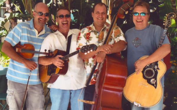 In a slightly blurry snapshot, the four members of Sviraj strike a candid pose with their instruments, bunching close together, grinning and laughing. They appear to be in their 40s.