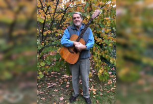Craig Zumbrun holding his guitar on a fall day outdoors